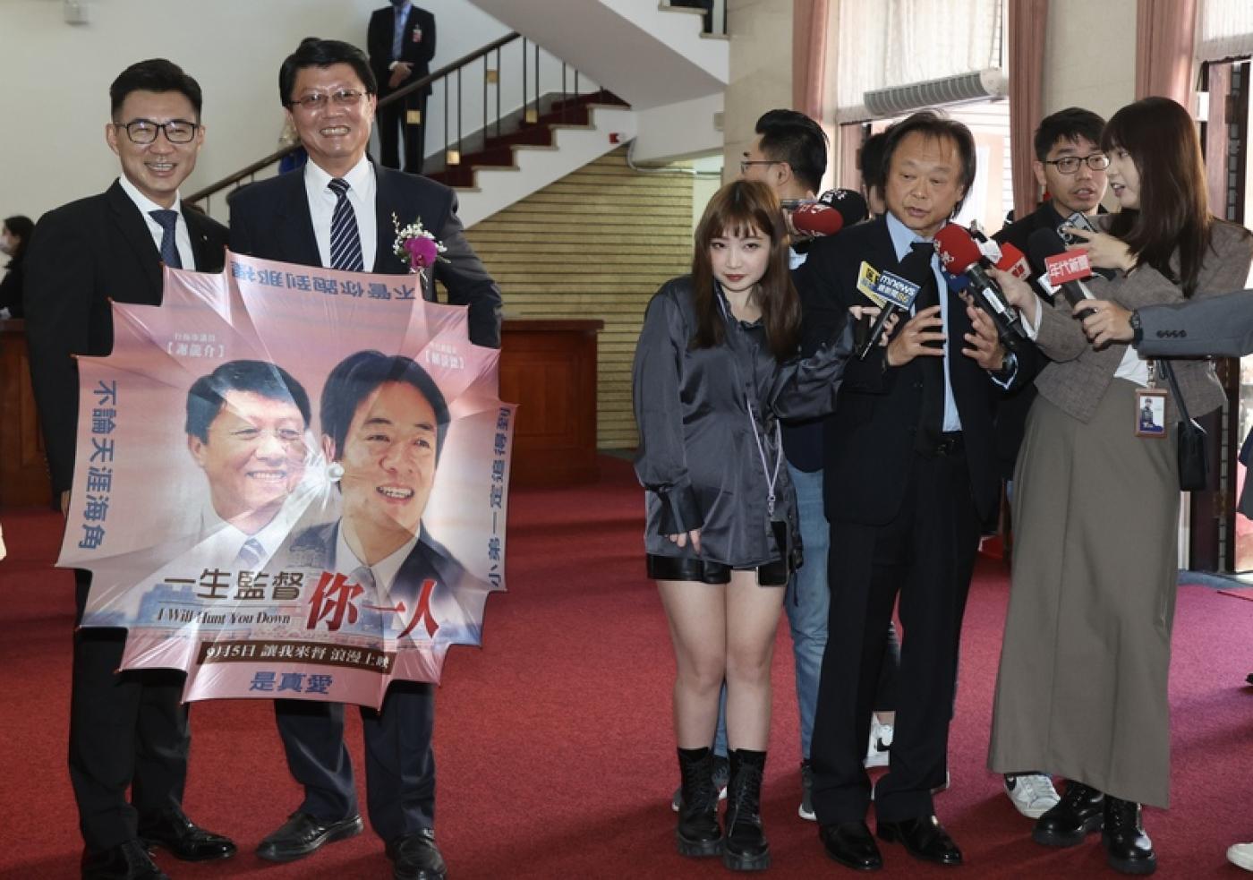 國民黨立委江啟臣（左）、謝龍介（左2）在民進黨立委王世堅（前右2）受訪時亮出自製雨傘，上面印有「一生監督你一人」字樣。中央社