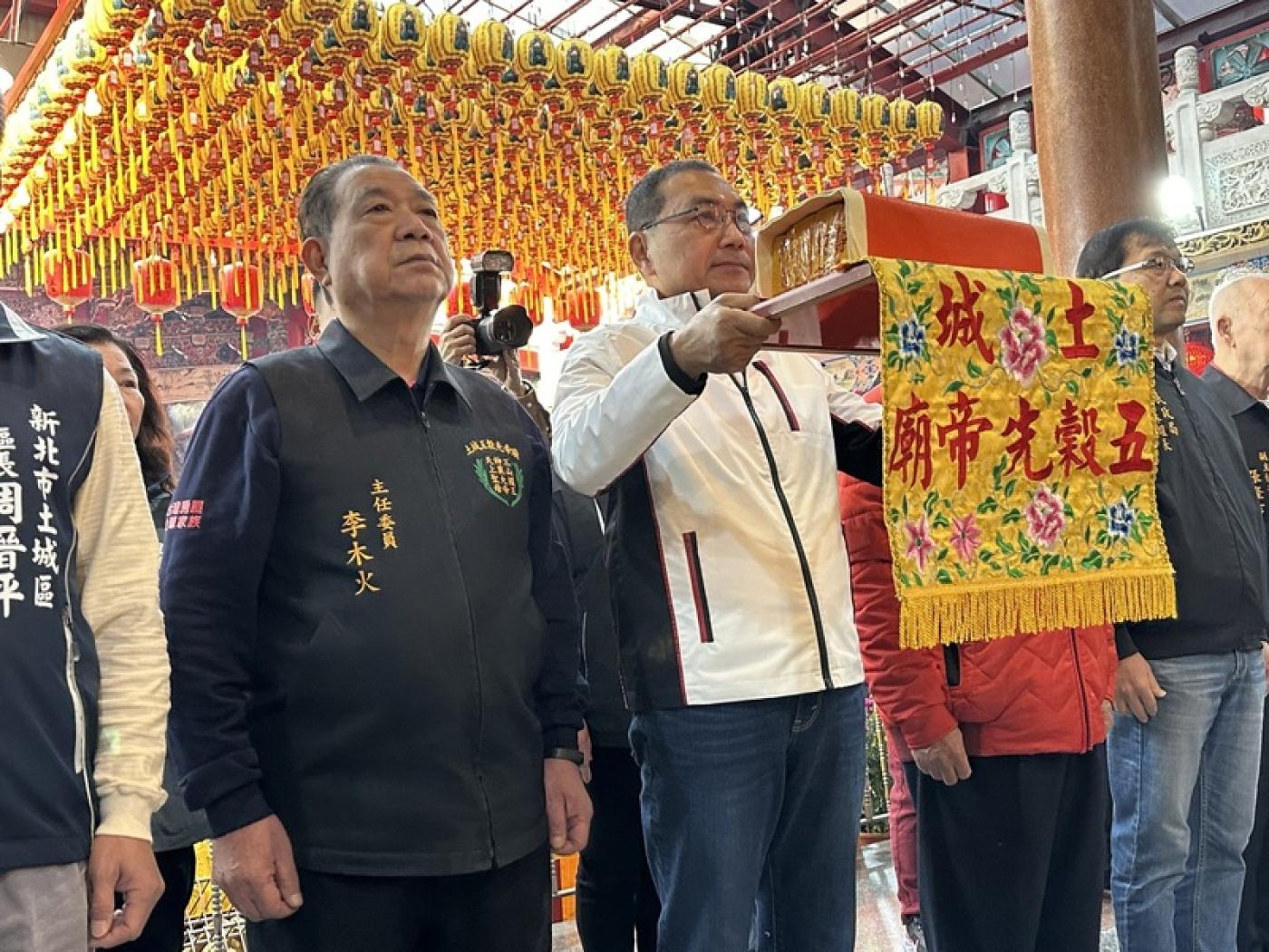 新北市長侯友宜（中）春節期間赴各地拜廟祈福並發放福袋，吸引許多民眾排隊領取。圖為侯友宜在土城五穀先帝廟參香。新北市民政局提供